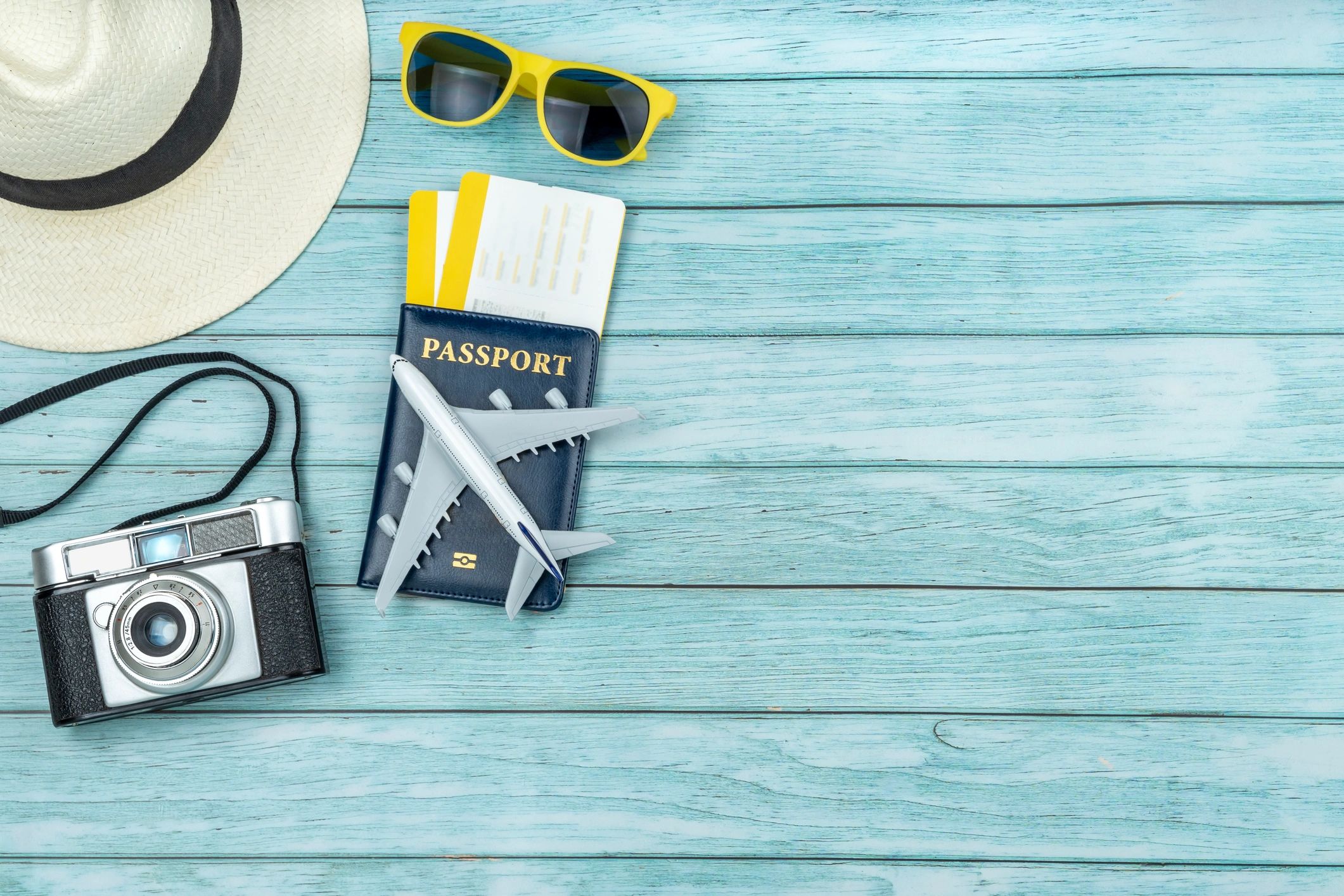 Flat lay of travel planning essentials with passport, boarding passes, camera, and sunglasses